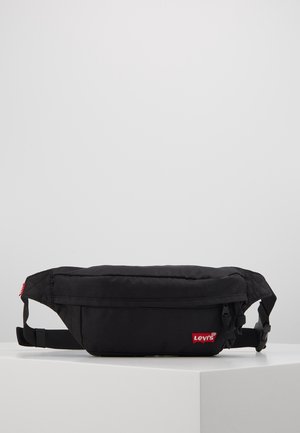 Schwarze Levi's-Gürteltasche mit Reißverschlussfächern und verstellbarem Riemen, auf einer weißen Plattform vor einem schlichten Hintergrund präsentiert.