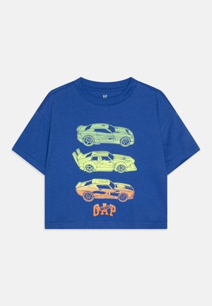 Modrá bavlnená tričko s krátkym rukávom s tromi neonovými grafikami áut v zelenej a oranžovej farbe, s logom "GAP" v tučnom písme na spodnej časti.