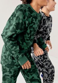 Sweatshirts et pantalons à motif camouflage vert et gris, dotés de poignets côtelés et de détails de texte imprimé, en tissu doux et texturé.