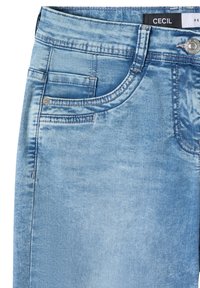 Jean en denim bleu clair délavé en gros plan montrant la poche avant, la boucle de ceinture, le bouton et l'étiquette de marque "CECIL" sur la ceinture.