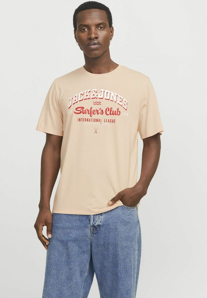 Beige katoenen t-shirt met korte mouwen en ronde hals. Voorzien van rode graphics met de tekst "JACK & JONES Surfer’s Club International League."