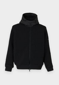 Crna zip-up majica s rebrastom teksturom, glatkom kapuljačom i vezicom. Ima dugačke rukave i elastične manžetne. Zatvarač na prednjoj strani.