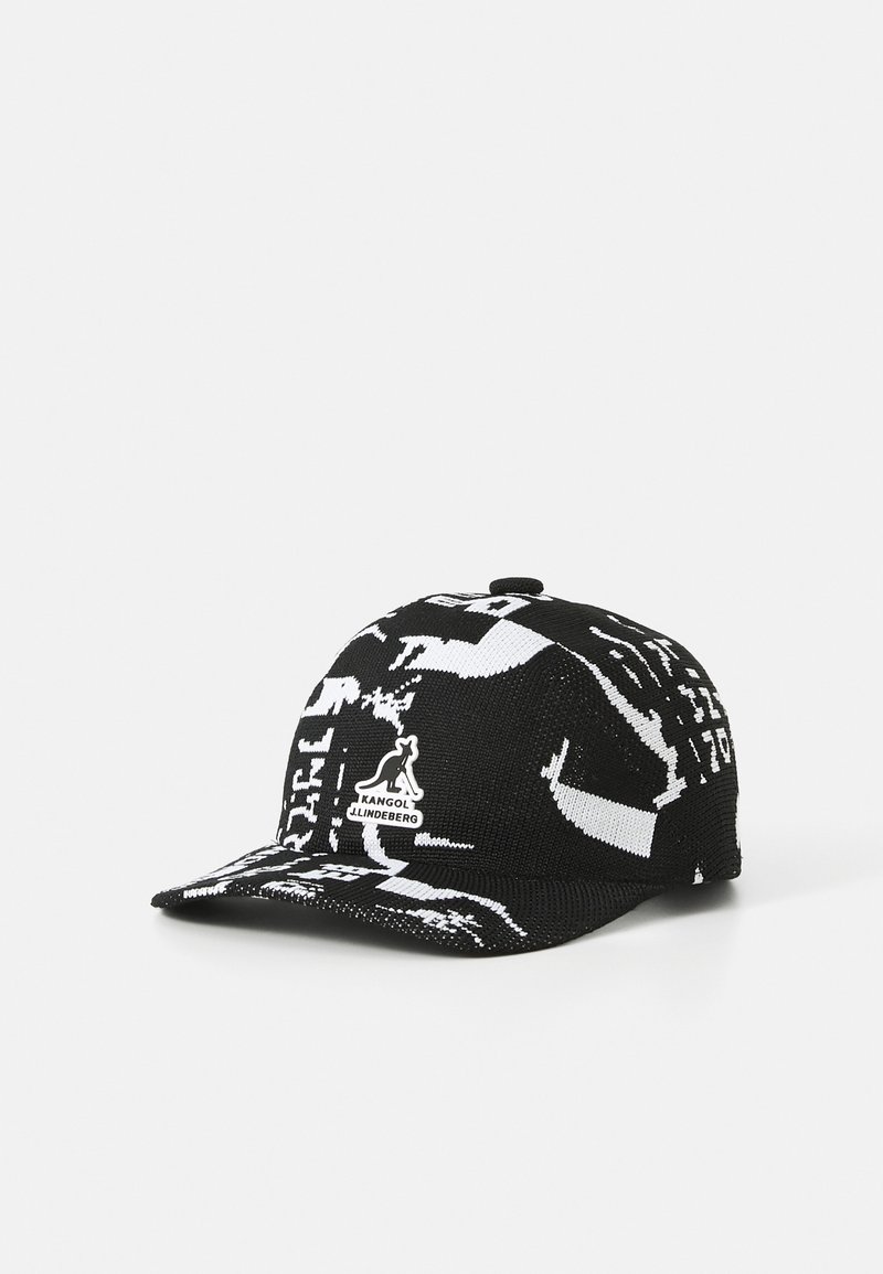 Gorra de punto en blanco y negro con ala curva, que presenta un estampado gráfico y una etiqueta de logo en la parte frontal. Tejido texturizado con un diseño deportivo.