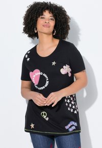 Camiseta negra de manga corta con estampados gráficos coloridos, que incluyen corazones, estrellas y texto. Presenta un escote redondeado y costuras verdes.
