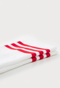 Weiße Socken mit drei roten Streifen oben, aus strukturiertem Stoff, ordentlich gefaltet.