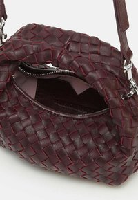 Borsa a tracolla in pelle borgogna intrecciata con cuciture a contrasto, chiusura con zip superiore e foderatura interna morbida. Presenta un manico corto.
