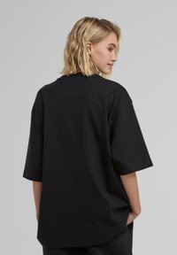 T-shirt nera oversize realizzata in tessuto morbido, con maniche corte, vestibilità rilassata e scollatura rotonda, dal tocco liscio.