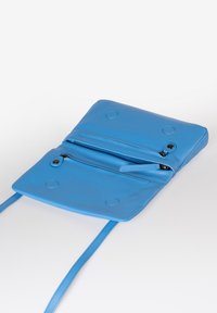 Borsa a tracolla in pelle blu con due scomparti, chiusura con zip e tracolla. Texture liscia, hardware minimale e dettagli circolari.