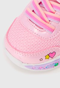 Baskets roses avec une tige en mesh, des accents texturés, des lacets superposés en rose et lavande, et des motifs décoratifs en forme de cœur et d'étoile.