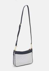 Crossbody taske med en navy læderrem, grå canvas krop med et gentagende "MK" mønster, hardware i guldtonet og lynlåslukning.