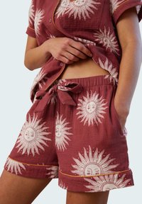 Maroon pajama set featuring sun graphic patterns in white. The short-sleeve shirt has a pocket, and the shorts have an elastic waistband with a drawstring.