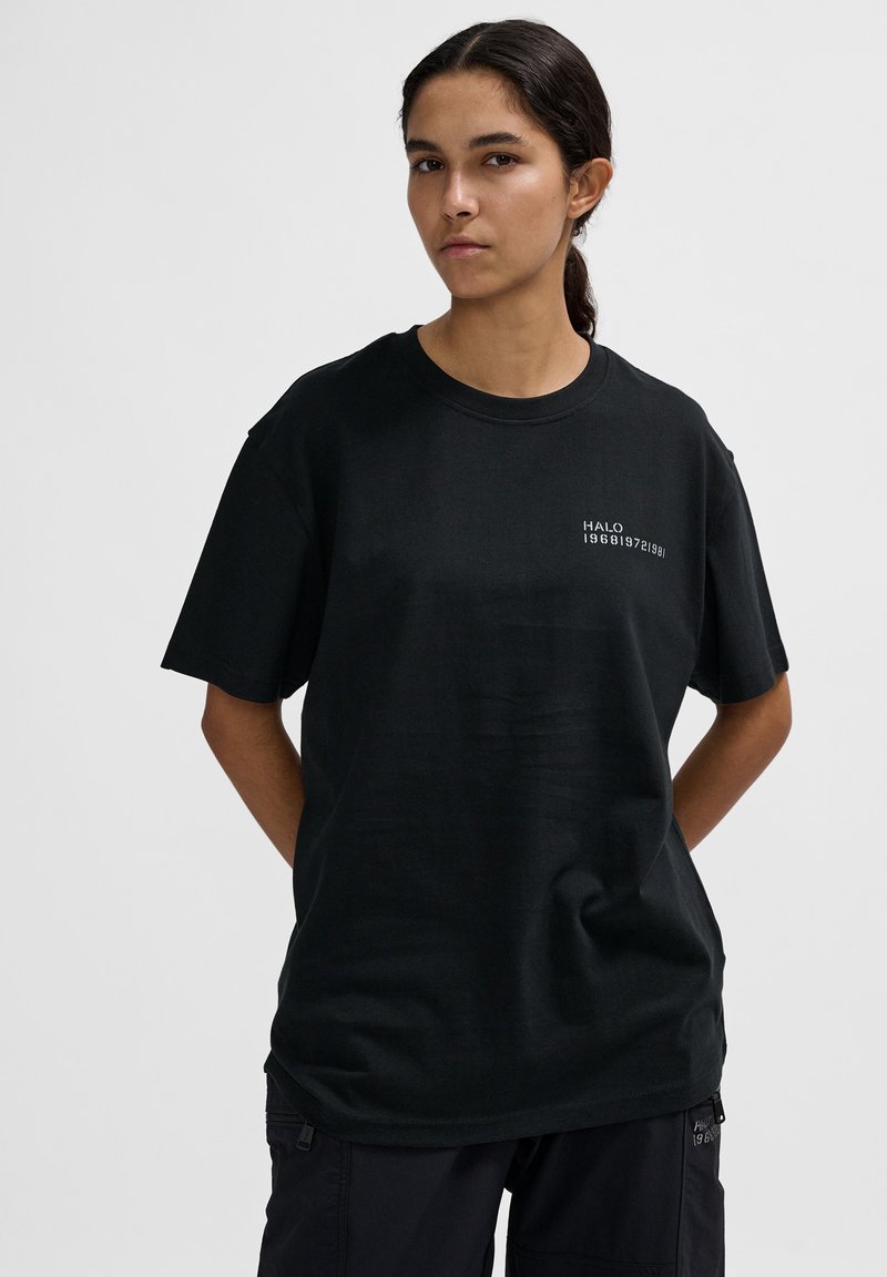 Schwarzes Baumwoll-T-Shirt mit Rundhalsausschnitt und kurzen Ärmeln. Auf der Vorderseite ist "HALO" in weißem Text gedruckt. Einfaches Design, lockerer Schnitt.