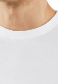 Maglietta bianca in cotone con collo rotondo. Il tessuto appare liscio con una leggera textura, mettendo in evidenza cuciture pulite attorno al collo.