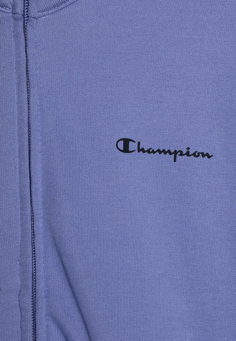 Felpa con zip di colore viola chiaro realizzata in morbido tessuto, con un logo "Champion" nero sul lato sinistro del petto e dettagli a coste testurizzati.