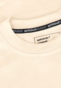 Beige katoenen t-shirt met een ronde halslijn en ribbeltrim, voorzien van een label met de tekst "spitzbub STUDIOS" en "original" op een binnenlabel.