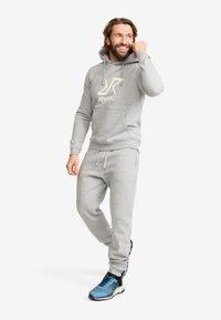 Grå hoodie och sweatpants-set i mjukt tyg, med en framficka och logotyp. Kommer med blå träningsskor med svart sula.
