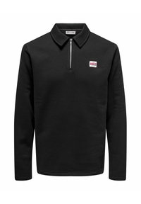Sweatshirt zippé noir avec manches longues, fabriqué en tissu doux. Il présente un petit logo rouge et blanc sur la poitrine gauche.