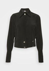 Černý zkrácený top s kolorou, dlouhými rukávy a stříbrnými knoflíkovými detaily na přední straně. Vyrobeno z hladké, lehké látky.