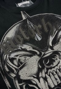 Čierne bavlnené tričko s sivou grafikou lebky a slovom "Motorhead" v tučnom, reliéfnom písmene. Textúrované detaily po celom tričku.
