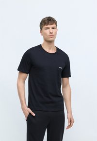 Black short-sleeve t-shirt made of cotton, featuring a round neckline and small white "BOSS" logo on the left chest. Simple design.