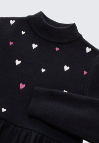 Strickpullover in Marineblau mit hohem Kragen und langen Ärmeln, verziert mit gestickten kleinen Herzen in Rosa, Weiß und Creme über das gesamte Design.