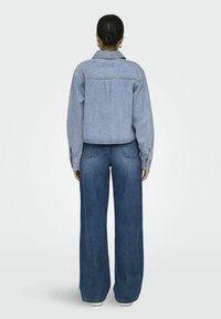 Denim jacket in light blue with contrasting stitching, paired with wide-leg blue jeans. Both pieces feature a casual design and texture.