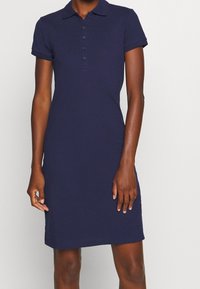 Robe polo bleu marine en coton, avec un col, des manches courtes, une patte de boutonnage et une silhouette ajustée.