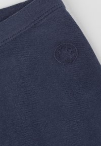 Abbigliamento in cotone navy con una superficie liscia, caratterizzato da un sottile patch logo in rilievo sul lato e un orlo pulito e rifinito.