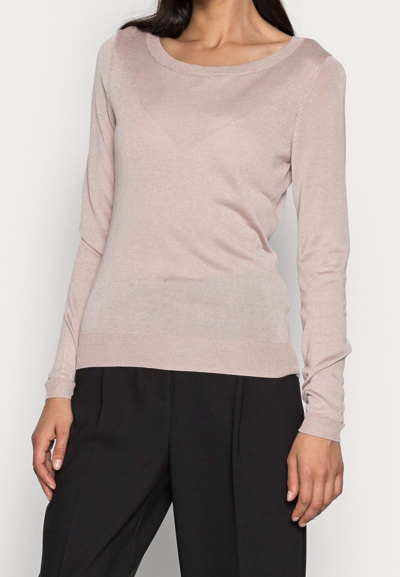 Pull en maille rose clair avec des manches longues, un col rond et des poignets et un ourlet côtelés. Texture douce, design ajusté et détails minimalistes.