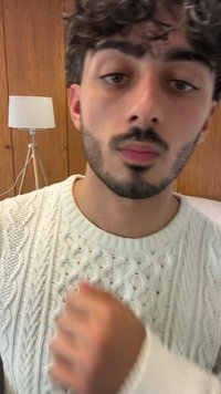 Pull en tricot torsadé de couleur écru, présentant des textures et des motifs complexes. Fond de la pièce avec du bois clair et une lampe sur pied.