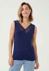Top senza maniche blu navy con scollo a V e rifinitura in pizzo. Tessuto morbido, vestibilità comoda e design semplice. Abbinato a jeans azzurri chiari.