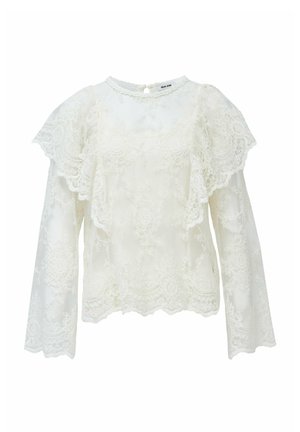 Haut en dentelle blanche avec de longues manches évasées, des bords festonnés et un col rond avec une fermeture en trou de serrure à l'arrière.