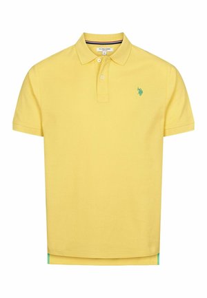 Sárga pamut póló, két gombos nyakkal, zöld hímzett logóval a bal mellrészen, és kontrasztos kék szegéllyel az alján.