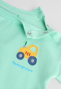 Mintgroene baby romper met een gele en blauwe geborduurde tractor en de tekst "homegrown" eronder, met drukknopen op de schouder.