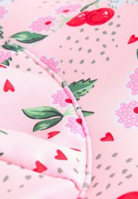 Pink fabric featuring floral and heart patterns, with cherries, leaves, and decorative stitching. Soft, smooth texture with subtle sheen.