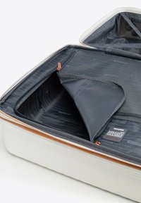 Maleta rígida en blanco con exterior texturizado, que presenta un interior gris con compartimentos con cremallera y un bolsillo de malla. Cremallera de color óxido.