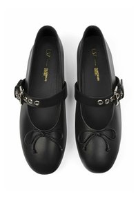 Bailarinas de cuero negro con puntera redondeada, detalle de lazo y una correa ajustable con herrajes de plata y remaches.