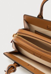 Borsa a mano in pelle marrone con cerniere dorate, dotata di due scomparti e interno beige liscio. Dettagli comprendono una robusta maniglia superiore.