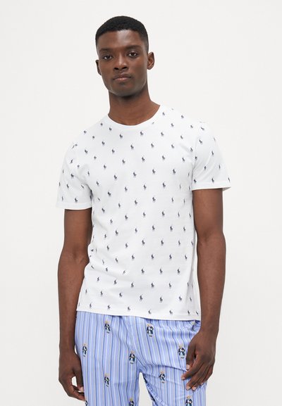 T-shirt en coton blanc avec un col rond et un motif répétitif de logo de poney marine, associé à un pantalon rayé bleu orné de petites illustrations de personnages.