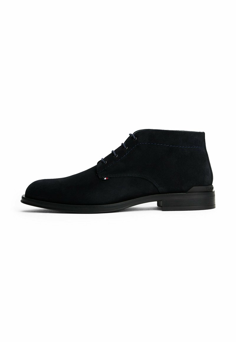 Stivaletto da uomo in suede nero, con punta rotonda, lacci anteriori, tacco basso e piccolo tag del marchio tricolore sul lato.
