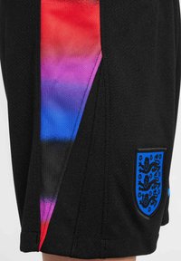 Shorts de sport noirs avec un design en dégradé rouge, violet et bleu sur le côté, avec un emblème en forme de bouclier bleu et un tissu texturé.