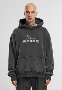 Sötét szürke kapucnis pulóver elülső zsebbel és "Én leszek az AMUSE-BOUCHE-d" felirattal rózsaszín és fehér színben. Pamut anyag, laza szabás és húzózsinóros kapucni.