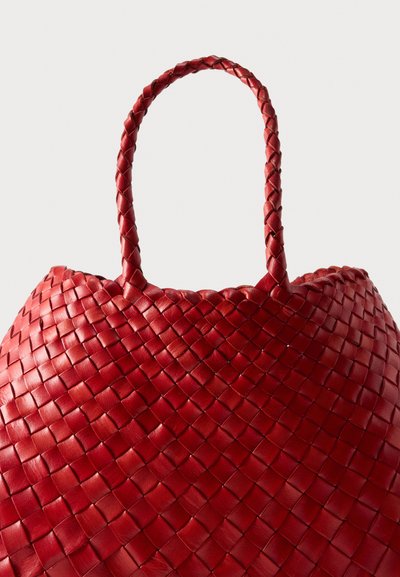 Κόκκινη υφασμένη δερμάτινη τσάντα με πλεγμένες λαβές σε απλό ανοιχτό φόντο.