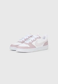 White sneakers with light pink accents, featuring a smooth leather upper, textured side panels, perforated toe, and white laces.