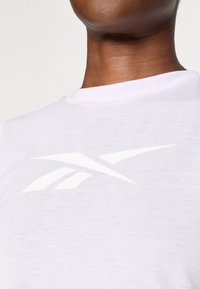 Biele bavlnené tričko s okrúhlym výstrihom. Má veľké, vyvýšené biele logo Reebok na hrudi, čo dodáva čistý dizajn.