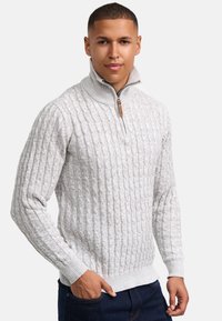 Hellgrauer Strickpullover mit hohem Kragen, der ein strukturiertes Zopfmuster und einen Viertelreißverschluss mit Holzakzenten aufweist.
