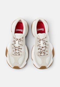 Sneaker bianca e beige dal design spesso, con pannelli testurizzati, lacci metallici e una soletta rossa con il marchio "CAMPER".