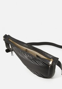 Borsa a tracolla nera in pelle con texture a coste, zip dorata e interno beige. Include una lunga tracolla regolabile per un facile utilizzo.