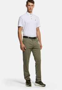 Korte mouwen witte poloshirt met een kraag, gecombineerd met olijfgroene cargobroeken. De outfit bevat een zwarte riem en casual sportschoenen.