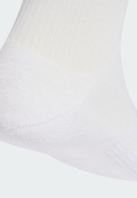Bijele pamučne čarape s ribastom teksturom, glatkim šavom na prstima i ojačanim petom. Jednostavan dizajn nudi svestranu opciju pribora.